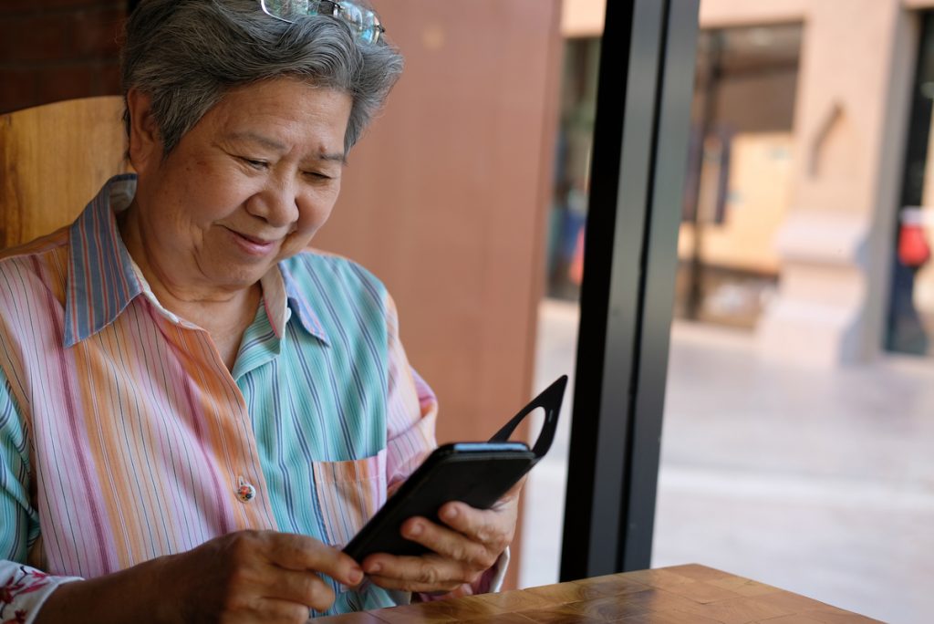 Old lady smiling while looking at her phone